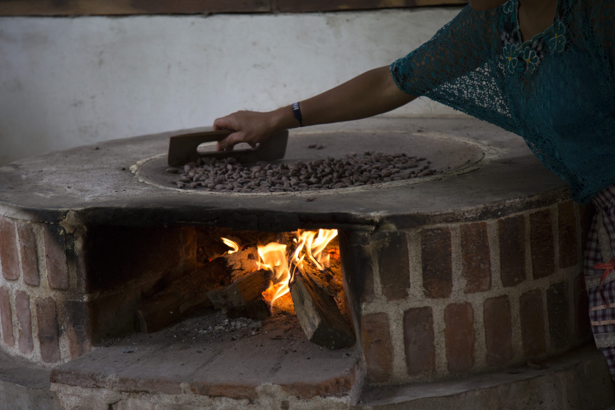Cacao beans being roasted by hand over an open fire