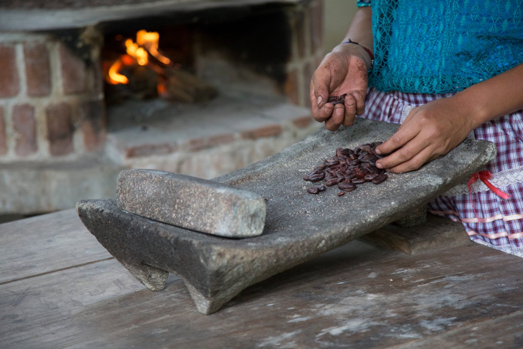 Roasted cacao beans on the metate, the grinding stone, in front of the open fire