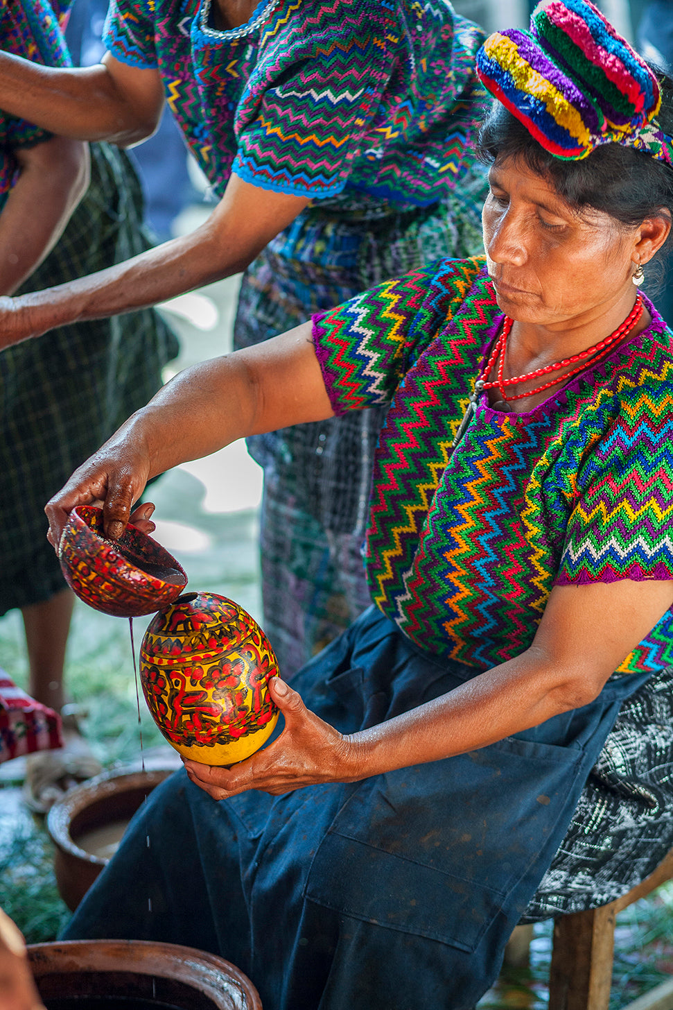 A Maya woman from Rabinal pours cacao from a height from one vessel into another to create foam